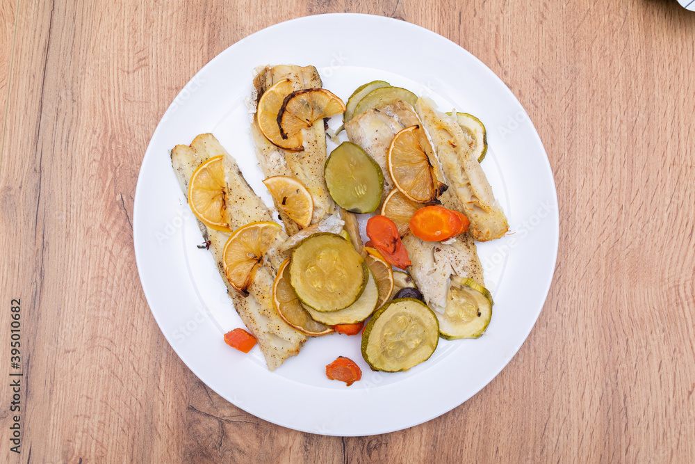 Fillet of sea fish with lemon slices and vegetables. Baking fish in the oven.