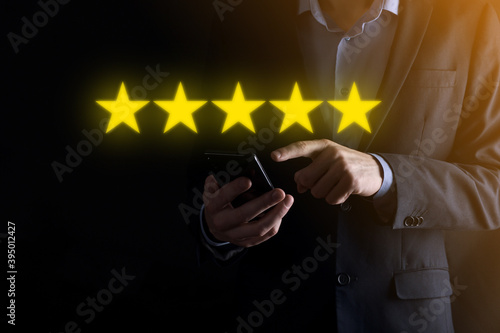 Fototapeta Naklejka Na Ścianę i Meble -  Man hand smartphone showing on five star excellent rating.pointing five star symbol to increase rating of company.Review, increase rating or ranking, evaluation and classification concept