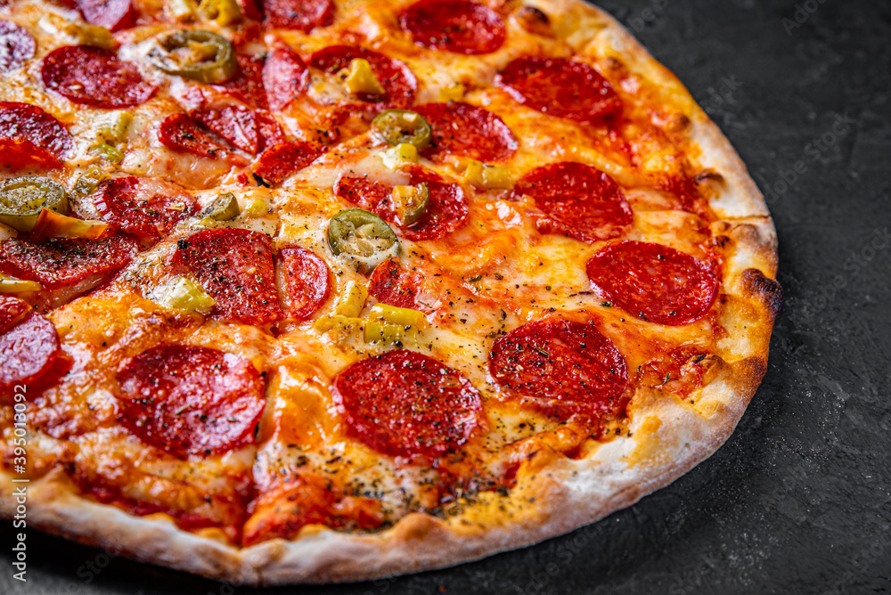 Pepperoni Pizza with Mozzarella cheese, salami, Tomato sauce, pepper, Spices. Italian pizza on Dark grey black slate background Pepperoni Pizza with Mozzarella cheese, salami, Tomato sauce, pepper, Spices. Italian pizza on Dark grey black slate background