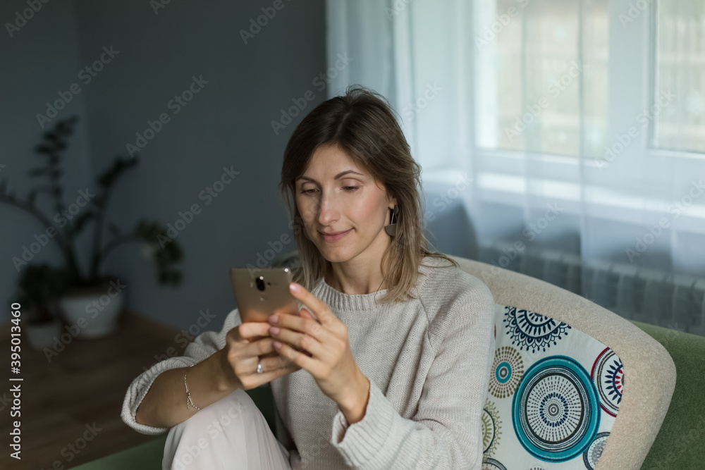 A beautiful girl sits and looks thoughtfully into the phone into the phone. A beautiful girl sits and looks thoughtfully into the phone into the phone.