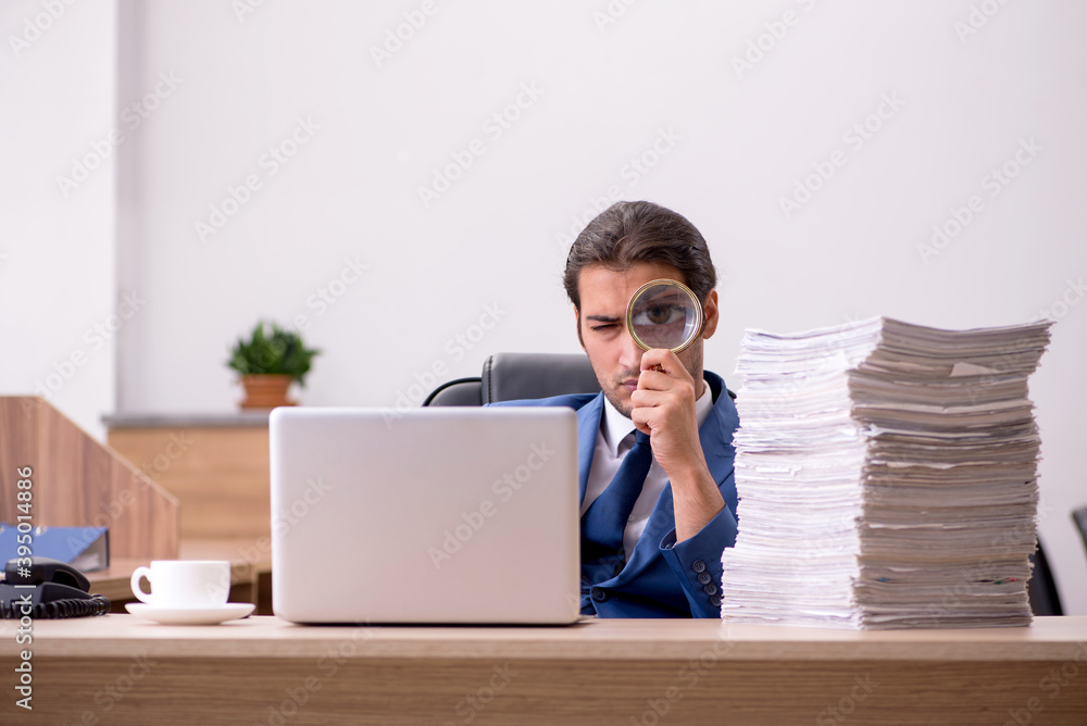 Young male employee unhappy with excessive work in the office Young male employee unhappy with excessive work in the office