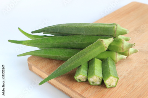 Fresh vegetable okra on wooden tray on white background       