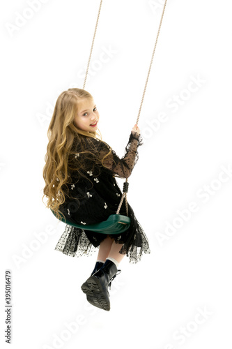 Happy little girl schoolgirl swinging on a swing.