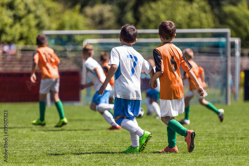 Boys playing in a soccer match. Football youth players kicking football ball in sunny day. Football competition tournament for school kids. Elementary age kids in white and orange sportswear © matimix