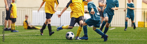 Horizontal image of football players kicking match. Boys in soccer duel. Kids in two football teams running after classic soccer ball. Horizontal sports background. Legs of young players on football