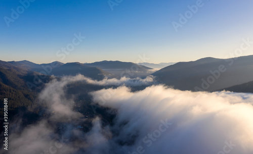 Aerial view of mountain landscape with low clouds at sunset.