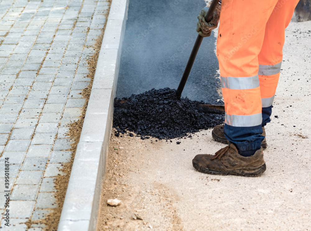 Worker regulate laying new asphalt to patch a bump in the road. Worker regulate laying new asphalt to patch a bump in the road.