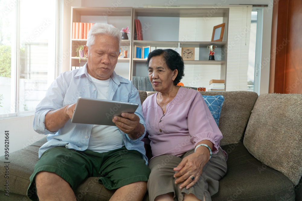Happy Asian senior couple use the tablet for Find vacation destinations in the holiday season. Concept of happy elderly lifestyle after retired Happy Asian senior couple use the tablet for Find vacation destinations in the holiday season. Concept of happy elderly lifestyle after retired