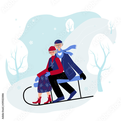 Seniors couple slide down the hill on the sleigh. Old people spend winter days outdoors in the open air.