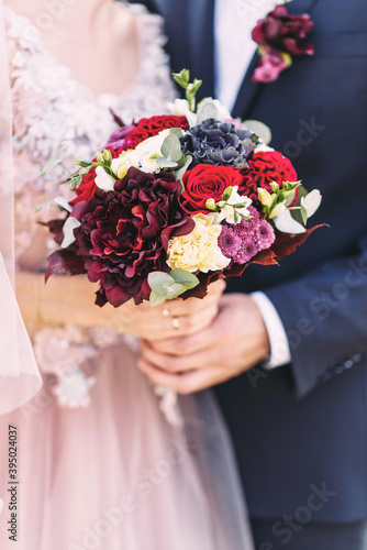 Fototapeta Naklejka Na Ścianę i Meble -  Beautiful wedding bouquet in the hands of the bride and groom
