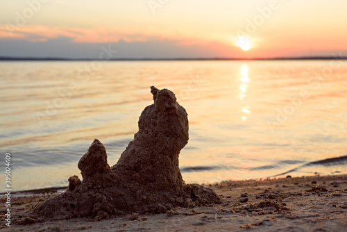 View of the beach with the figure of a cat made of sand by the sea at sunset