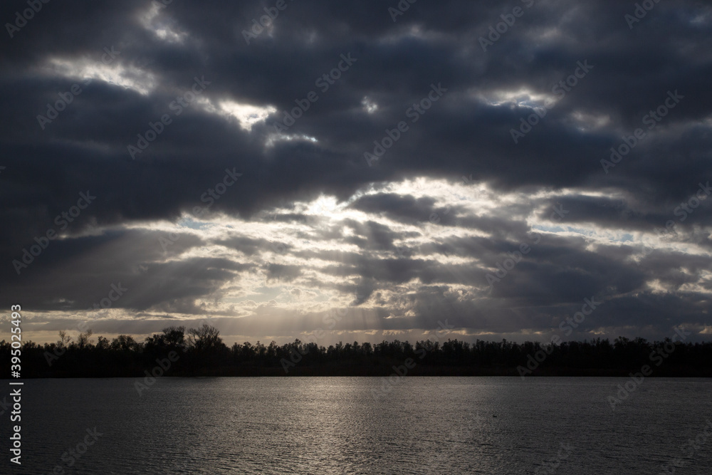 Rays of sun through dark clouds;  Biesbosch Natioanl Park, North Brabant, Netherlands