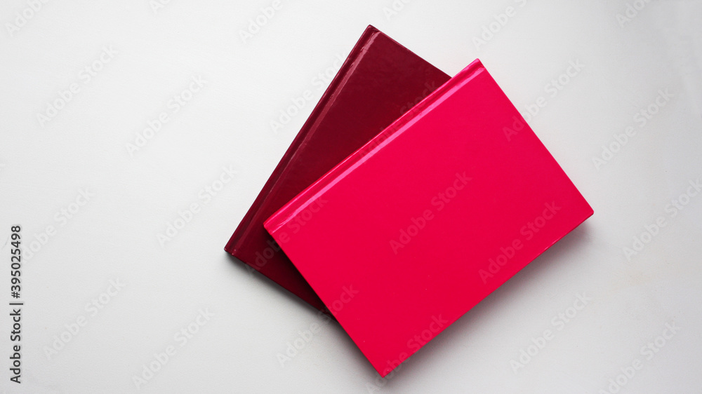 Colored notepads (pink and red) on a white background. Office. Top view, flat lay, minimal workspace. Colored notepads (pink and red) on a white background. Office. Top view, flat lay, minimal workspace.