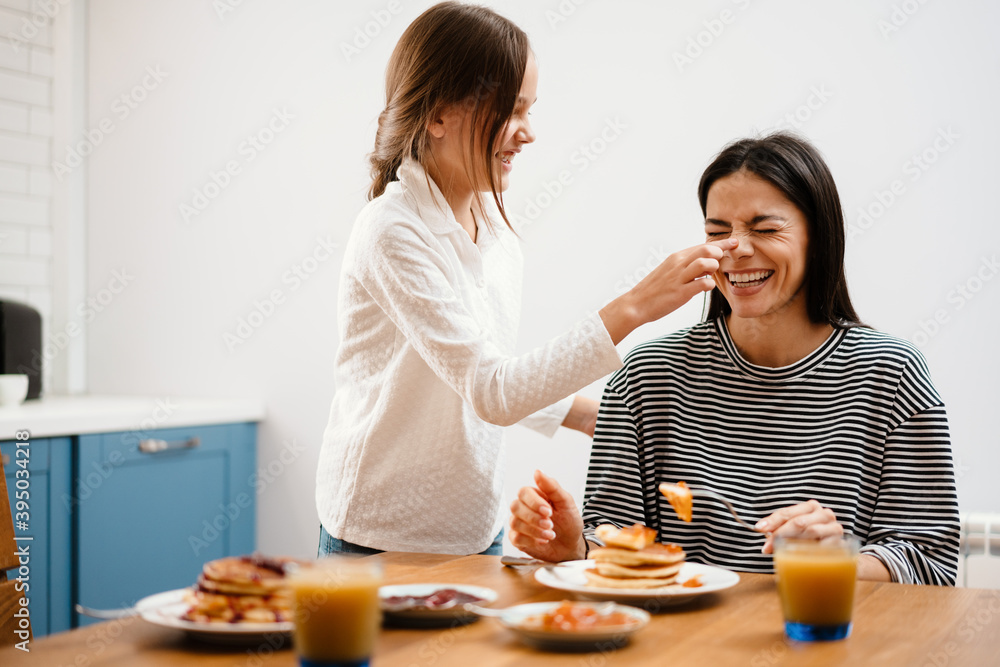 Cheerful mother and daughter making fun while having breakfast Cheerful mother and daughter making fun while having breakfast