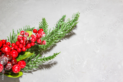 Christmas fir tree branches, red rowan berries with snow on grey background. Flat lay, top view. Copy space.