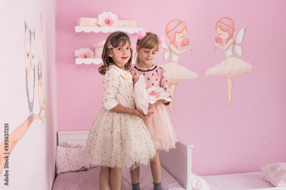Cute, little girls, sisters, twins standing on the bed in their lovely pink room Cute, little girls, sisters, twins standing on the bed in their lovely pink room