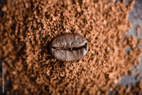 Fresh roasted coffee bean lays on heap of grinded coffee