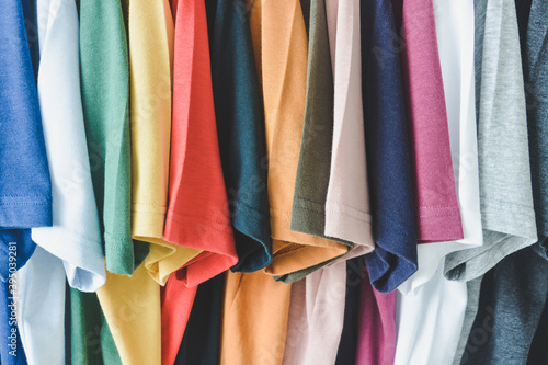 close up collection of colorful t-shirts hanging on clothes hanger in closet or clothing rack