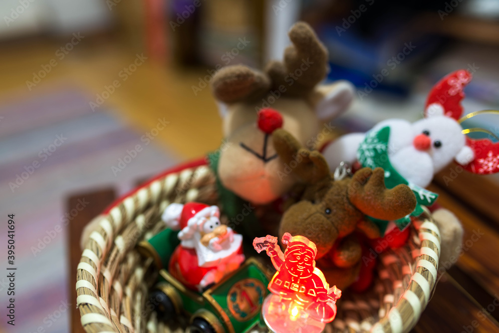 Colorful Christmas plush animals and snowman toys in a wooden basket, focus on the led illuminated snowman.