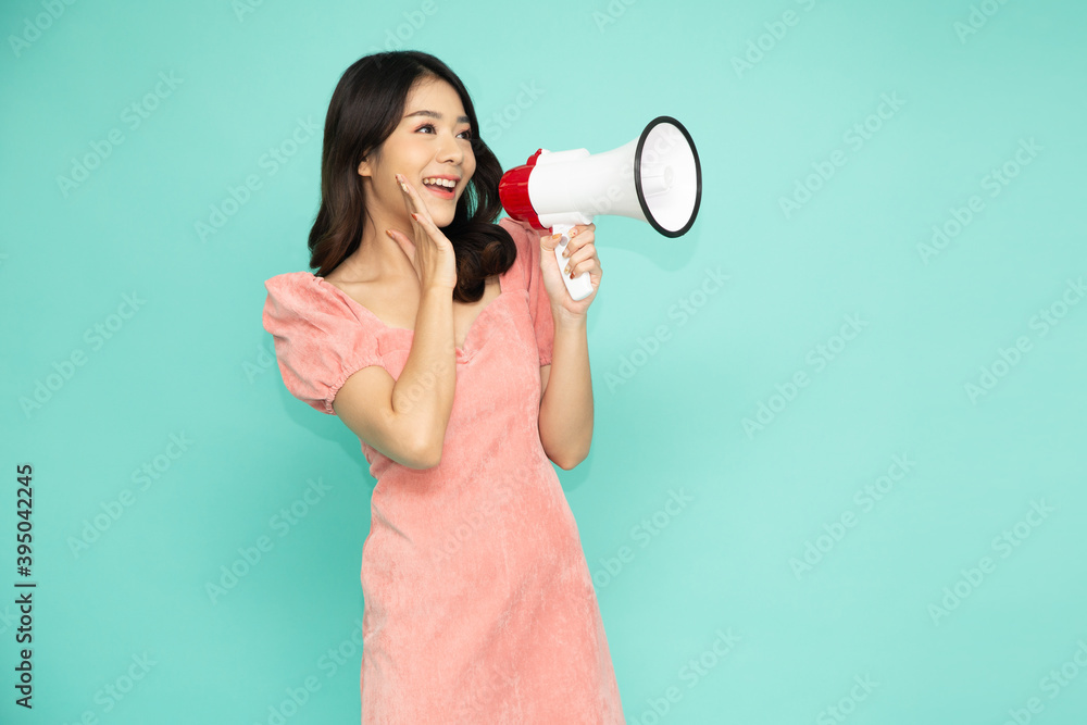 Young Asian woman holding megaphone isolated on green background, Speech and announce concept Young Asian woman holding megaphone isolated on green background, Speech and announce concept