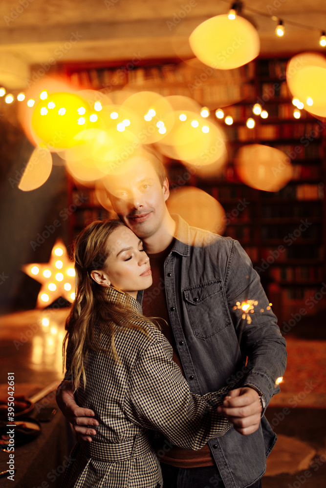 Lovely couple cuddling at home, charming husband hold sparklers, enjoy festive mood, cozy winter holidays, New Year and Christmas celebration concept