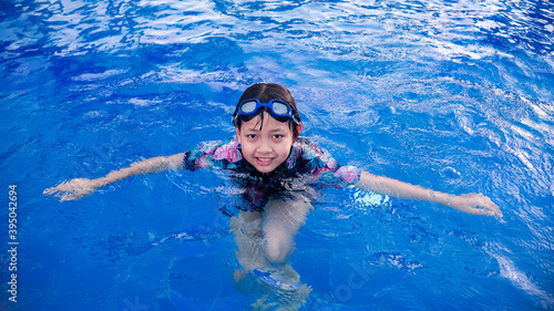 Pretty little girl in swimming pool with smile and happy in summertime.16:9 style