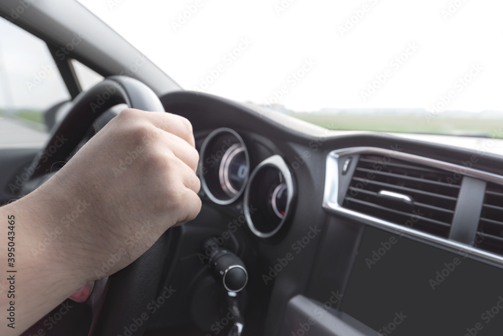 Man's hand on the steering wheel in the car.