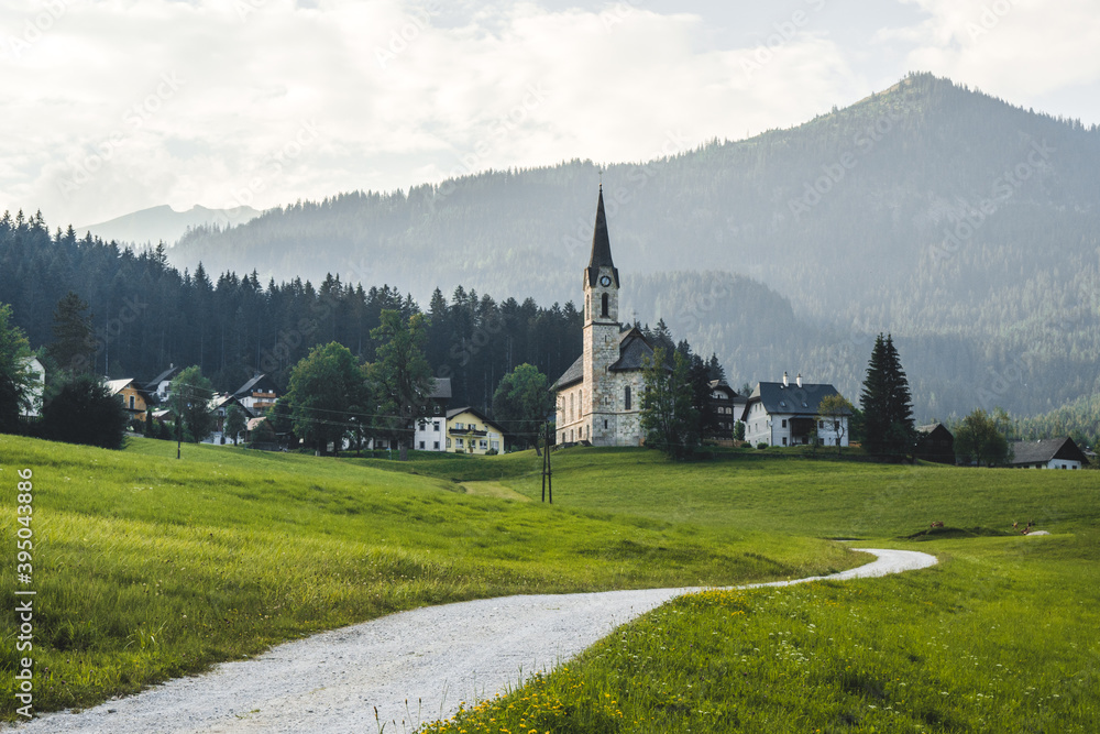 Fototapeta premium Road to a traditional picturesque church in Austrian Alps, Europe. Beautiful day in dummer