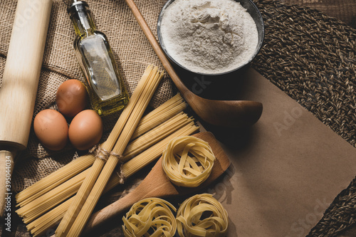 Ingredients for making pasta on a wooden background. Copy space. Uncooked pasta with flour on the table. Copy space