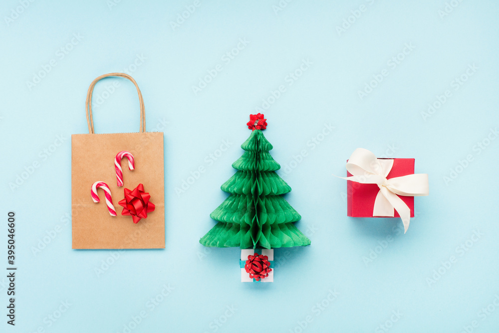 Winter Christmas holiday shopping concept. Craft paper bag, Xmas green tree and gift boxes on blue background.