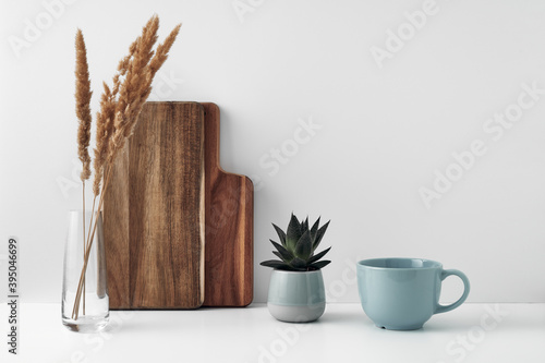 A mug, a potted houseplant, a clear vase and a wooden cutting board. Eco-friendly materials in the decor of the room, minimalism. Copy space, mock up.