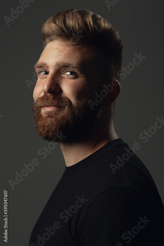 Fabulous at any age. Portrait of smiling 35-year-old man posing over gray background in black t-shirt. Close up. Hipster style. Red hair, modern haircut. Studio shot