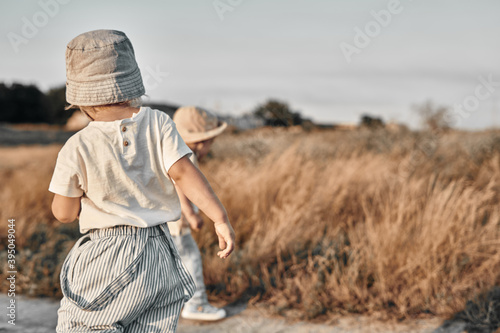 Two-year-old child in a hat walks along a country road, summer. Knowledge of the world. © Natalya Lys