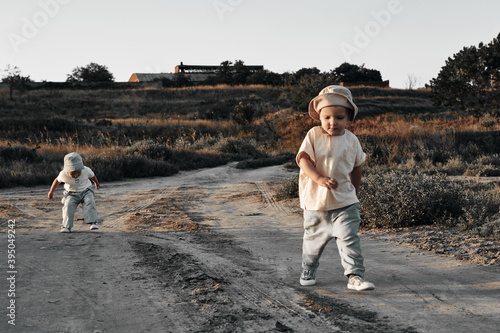 Two-year-old child in a hat walks along a country road, summer. Experience of the world. © Natalya Lys