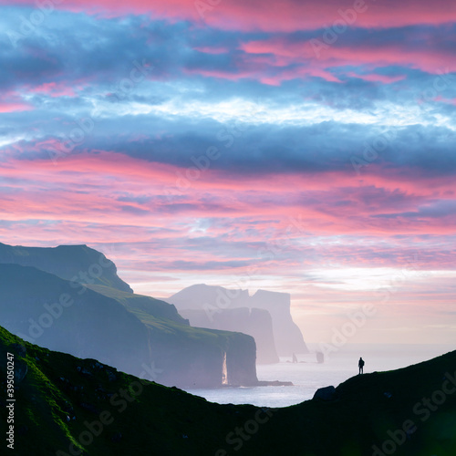 Man silhouette on background of famous Risin og Kellingin rocks and cliffs of Eysturoy and Streymoy Islands seen from Kalsoy Island. Faroe Islands, Denmark. Landscape photography photo