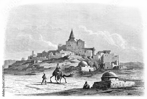 Jonah's tomb at Nineveh (destroyed by ISIS in 2014) on a desertic landscape with arabian small town. Ancient grey tone etching style art by Flandin, Le Tour du Monde, Paris, 1861 photo