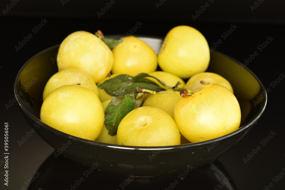 Several organic yellow plums, close-up, on a black background.