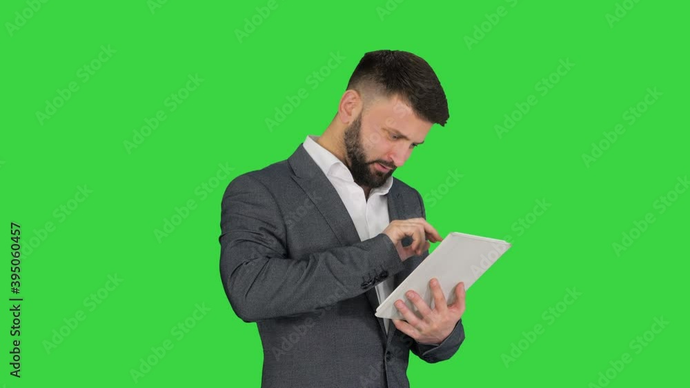 Turk business man with a beard standing and using tablet computer on a Green Screen, Chroma Key. Turk business man with a beard standing and using tablet computer on a Green Screen, Chroma Key.