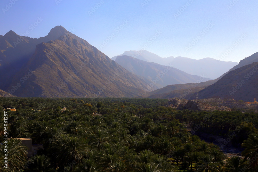 View of the arid mountain range, above the green palm grove, Nakhal, Al Batinah Region of Oman View of the arid mountain range, above the green palm grove, Nakhal, Al Batinah Region of Oman