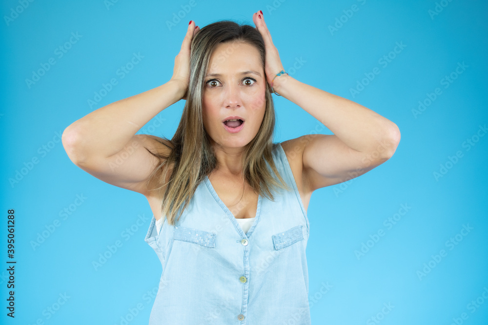 Image of excited screaming shocked beautiful woman standing isolated over blue background.