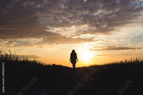sunset on the beach with rocks and sea and silhouette of a woman