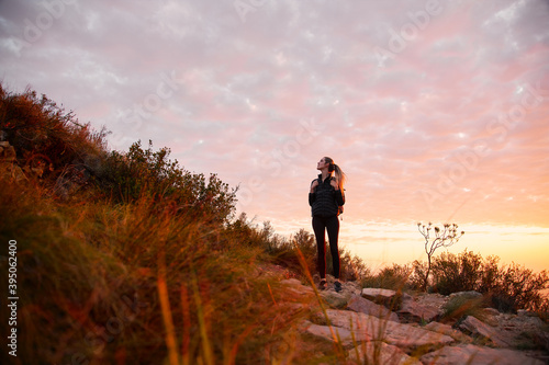 Front View Of Young Woman With Backpack Setting Off For Hike Along Countryside Path At Sunset