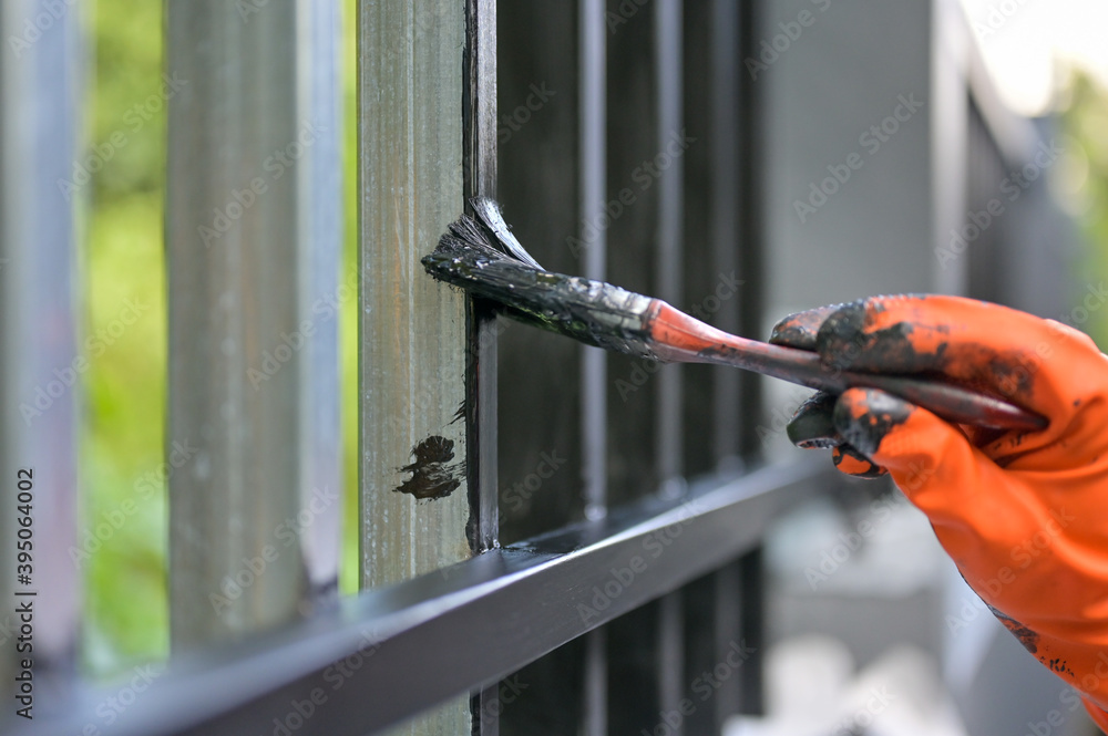 Worker painting steel with paint brush and orange gloves selective focus on hand Worker painting steel with paint brush and orange gloves selective focus on hand