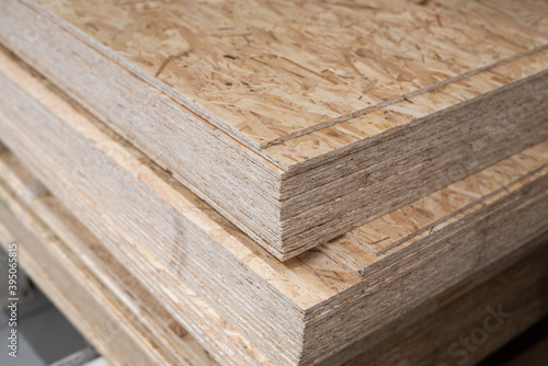 OSB sheets are stacked in a hardware store. The building material is wood.