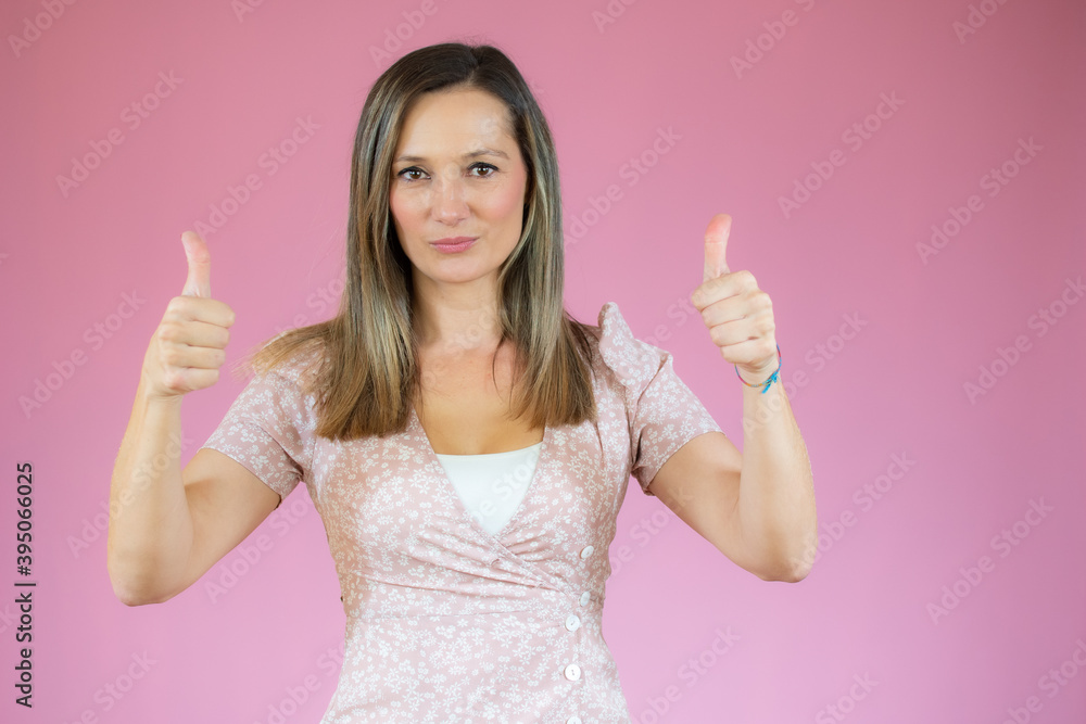 Young happy cheerful woman showing thumbs up over pink background. Young happy cheerful woman showing thumbs up over pink background.