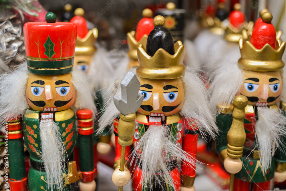 A wooden figures of a classic Nutcracker, in a green with red and gold uniform. With the white beard on the head, different hats. Christmas sale