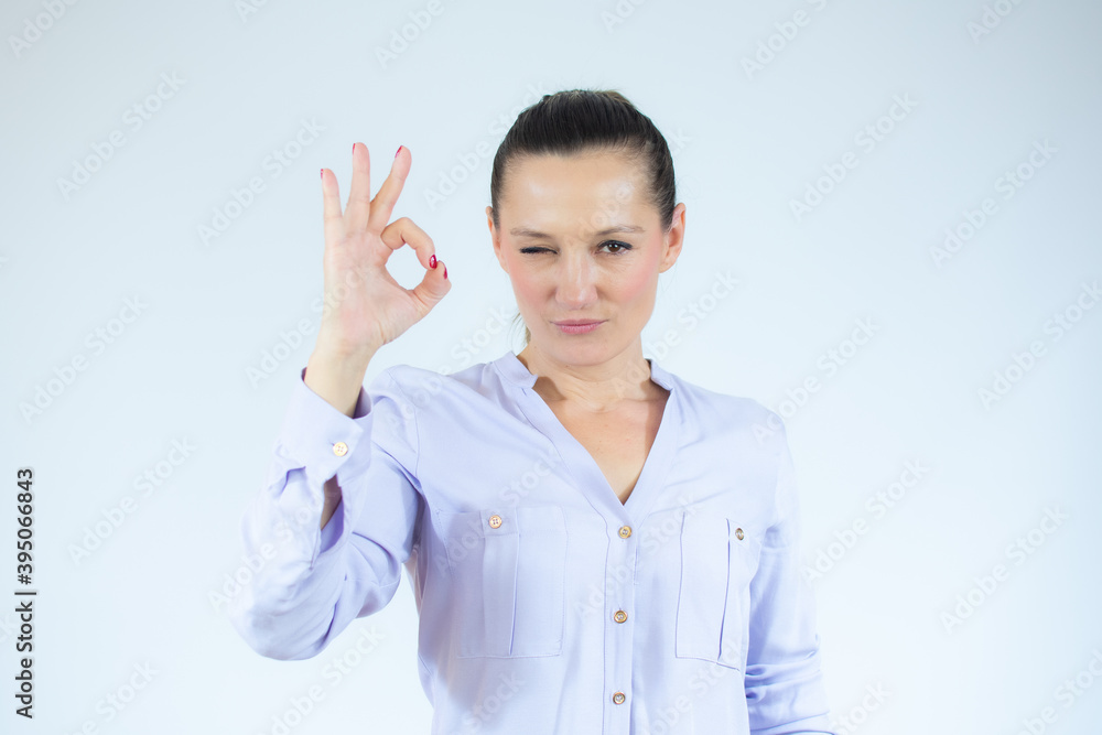 Beautiful woman standing over isolated white background doing okay sign with fingers, excellent symbol Beautiful woman standing over isolated white background doing okay sign with fingers, excellent symbol