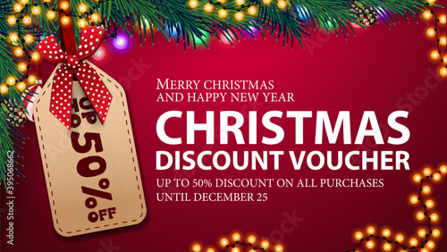 Pink Christmas discount voucher, up to 50% off on all purchases. Christmas voucher with large price tag, Christmas tree branches and garland frame