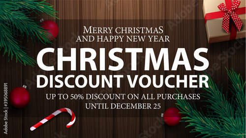 Christmas voucher, up to 50 off on all purchases. Christmas discount voucher with present, Christmas tree branches, candy canes, Christmas balls and wooden background, top view