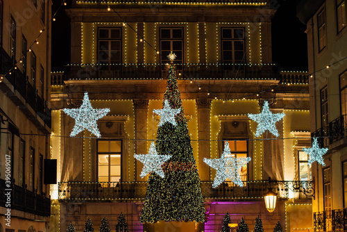 Facade of a building decorated with illumination in shape of stars and a Christmas tree during Christmas celebrations at night